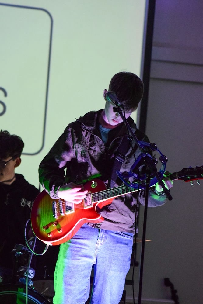 Guitarist mid-solo in green and red stage light